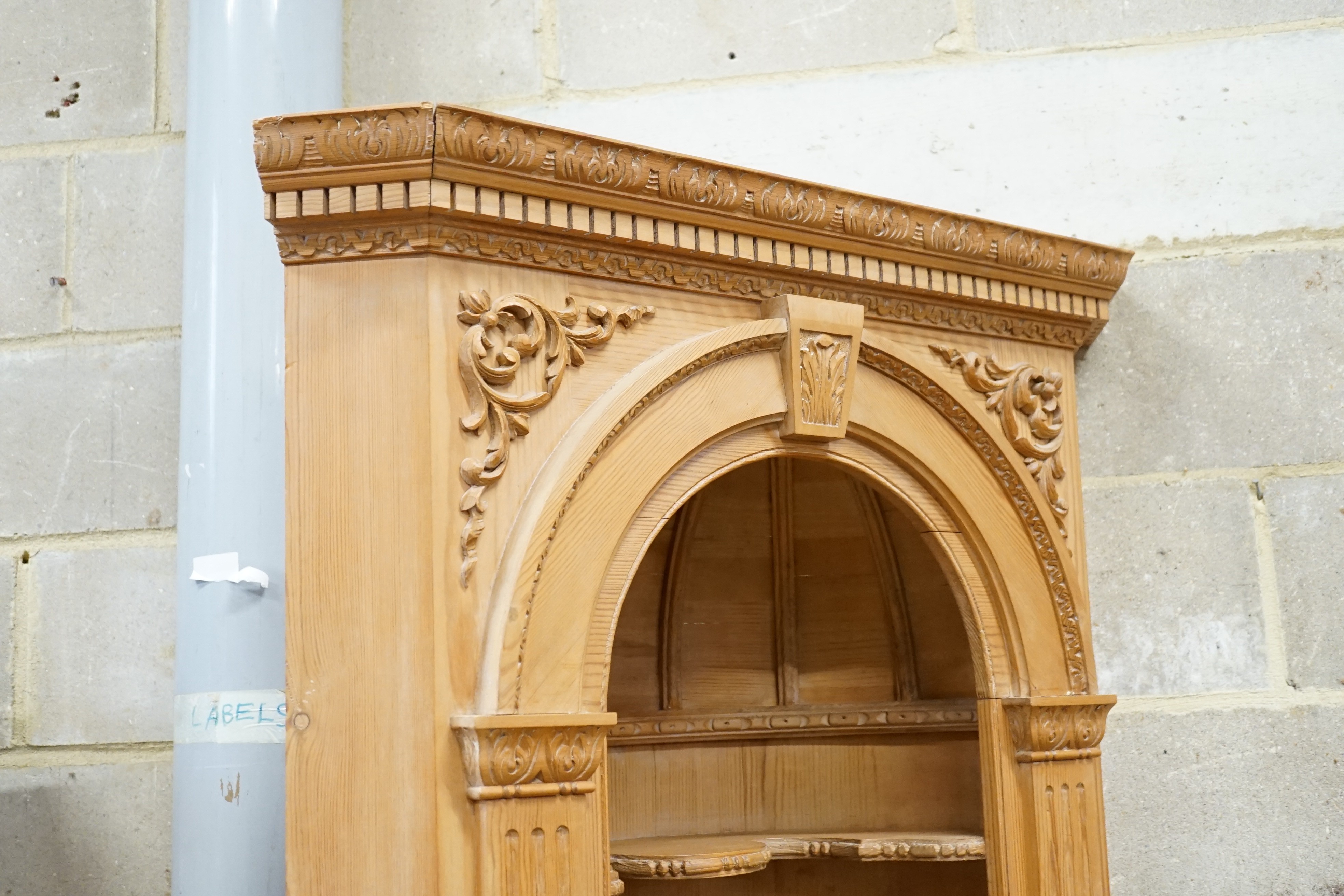An 18th century style carved pine standing corner cupboard with arched shelved recess, width 94cm, height 204cm